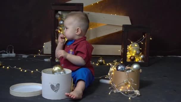 Kleine Jongen Zitten Amount Chrismas Lichten Het Houden Van Kerstbal — Stockvideo