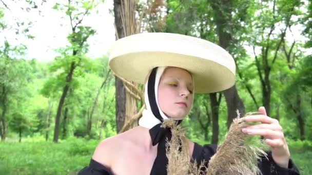 身穿黑色连衣裙 头戴雅致草帽的姑娘手里拿着一束干植物 — 图库视频影像