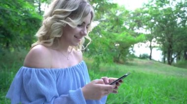 Bir yaz parkında rahatlamış genç bir bayanın 4K portresi üzerinde bir mesaj okuyor.