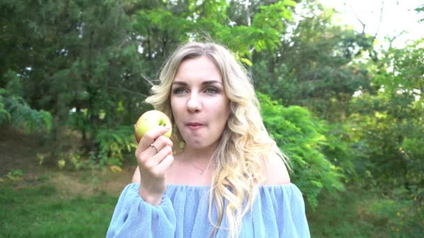 川沿いの公園の牧草地でリンゴを食べる4Kレディー — ストック動画