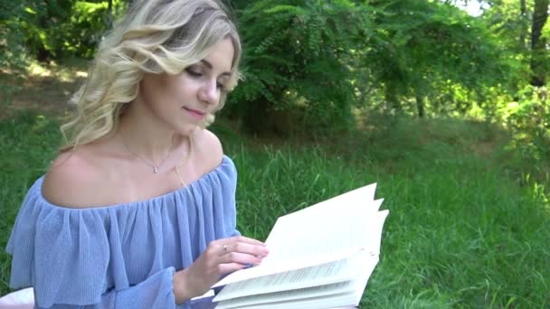 Hidas Motion Nuori Kaunis Nainen Hymyilee Lukee Kirjaa Vihreässä Puistossa — kuvapankkivideo
