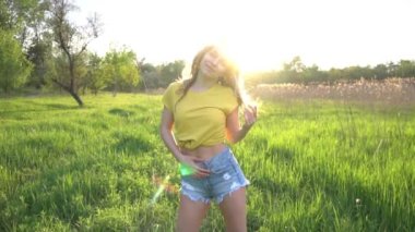 Yavaş çekim seksi kadın gün batımının çimen ışınlarında bir tarlada poz veriyor..