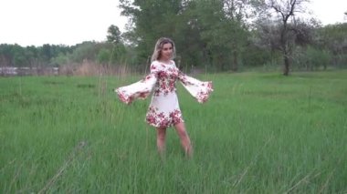 Yeşil tarlada beyaz elbiseli kız güneşli yaz gününün tadını çıkarıyor..