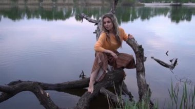 Güzel genç bir kadın nehir kenarında oturuyor ve hayal kuruyor