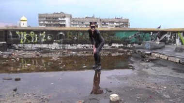 Mavi gökyüzünün önünde, çatıda duran siyah kedi kostümlü kadın.