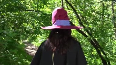 Woman witch in a hat and clothes in the forest gesticulate with her hands