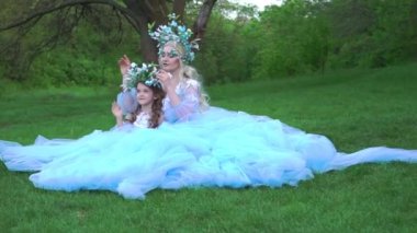 Beautiful mother with her daughter in blue dresses in the park 