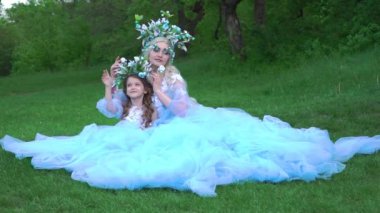 Beautiful mother and daughter in elegant airy cyan dresses with a train