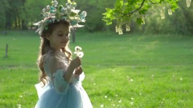 Başında çiçek çelengi olan küçük bir kız. Baharda mavi bir elbiseyle.