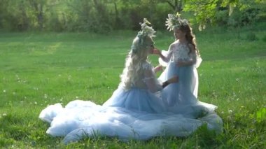 Woman with daughter in fashionable dresses. girl bride with child posing outdoor