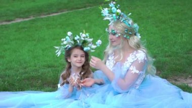 Mother and daughter in dresses in the beautiful summer green nature. 