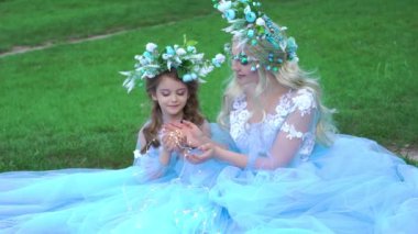 Slow Motion Family in the summer park. Mom with daughter in cyan dresses