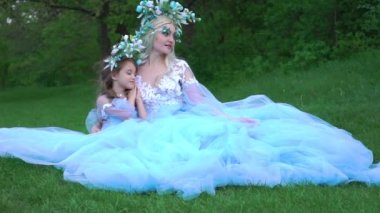 Güzel anne ve kız zarif, havalı, trenli bir Cyan elbisesi içinde.