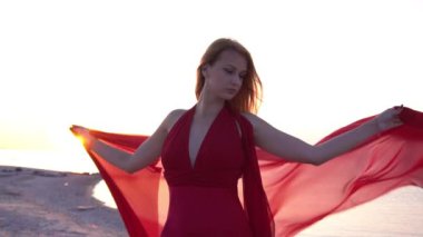 Deniz plajında kırmızı lüks uzun elbise li güzel genç kadın