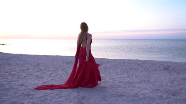 美しいですセクシー女の子でA赤ドレスでビーチを歩いて — ストック動画