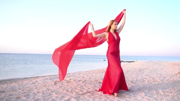 穿着红色衣服穿着风衣的美丽的自由女伴在海滩上缓缓前行 — 图库视频影像