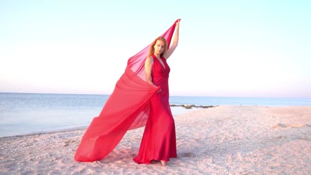 穿着红色衣服的金发女人在海滩上慢慢地走来走去 — 图库视频影像