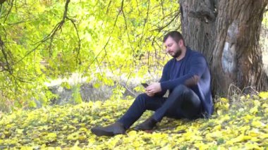 Slow Motion Handsome genç adam sonbahar parkında cep telefonu kullanıyor.