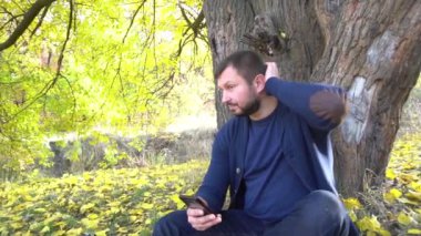 Slow Motion Sonbahar Ormanı 'nda cep telefonu kullanan neşeli, tıraşsız adam.