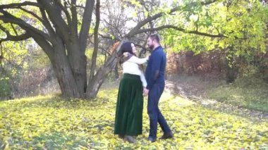 Erkek ve kadın güz mevsiminde güler parkta yapraklar dökülür, sonbahar gününün tadını çıkarırlar.