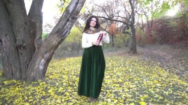 Slow Motion genç bayan sonbahar parkında çay içiyor.