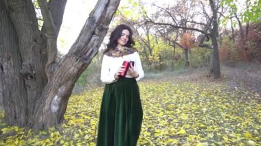 Slow Motion çekici kadın sonbahar ormanında kahve içiyor.