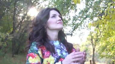 Slow Motion Smiling woman looking up against trees at park during autumn