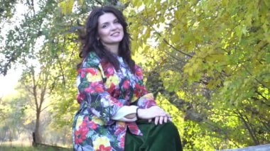 Slow Motion beyaz kadın sonbahar havasında ağacın altında poz veriyor.