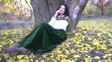 Slow Motion Güz Parkı 'nda cep telefonuyla konuşan mutlu genç bir kadın.