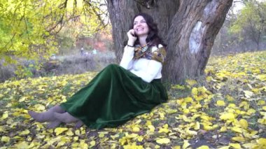 Cep telefonuyla konuşan güzel bir kadın sonbaharda doğanın tadını çıkarıyor. 