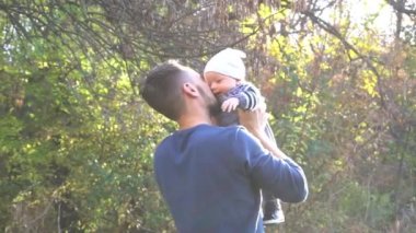 Slow Motion Bir baba bir sonbahar ormanında bebeğini kucağında tutuyor, eğleniyor..