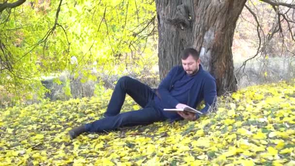 Slow Motion Young Man Reads Book Autumn Park — Stockvideo