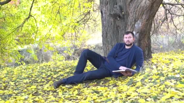 Slow Motion Young Man Reading Book Autumn Leaves — Vídeo de Stock