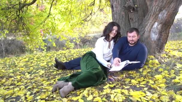 Slow Motion Couple Reading Book Old Tree Autumn Park — Stock Video