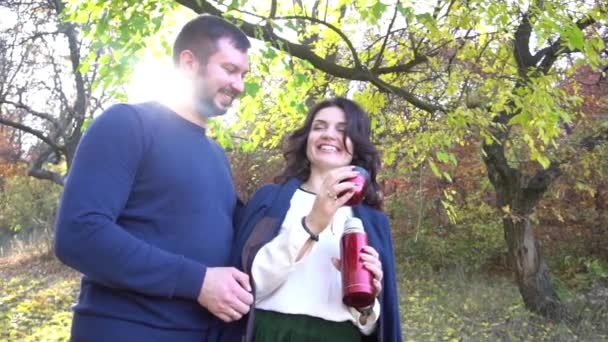 スローモーション晴れた秋の日に魔法瓶からお茶を注ぐカップル — ストック動画