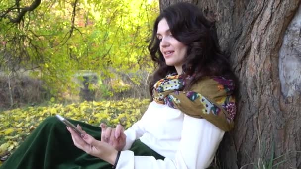 Vrouw Het Herfstpark Met Mobiele Telefoon Zittend Onder Een Boom — Stockvideo