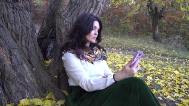 快乐美丽的黑发女人 调用通过电话在秋天的公园 — 图库视频影像