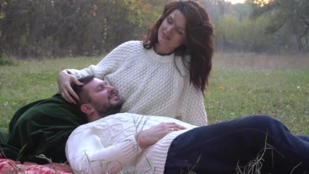 秋の紅葉の上に座るロマンチックなカップル — ストック動画