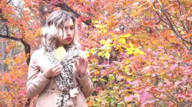 Yavaş hareket eden kadın portresi Sonbaharda doğada ağaçlar ve yapraklarla gülümsüyor