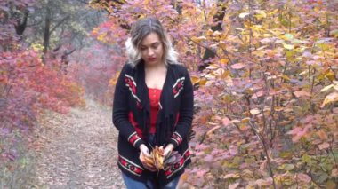 Heyecanlı mutlu kadın güler yüzlü, neşeli ve mutlu sonbahar yapraklarını dışarıda tutuyor.