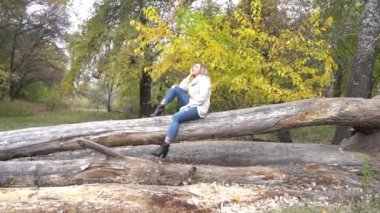 Güz parkında oturan ve poz veren çekici bir kız..