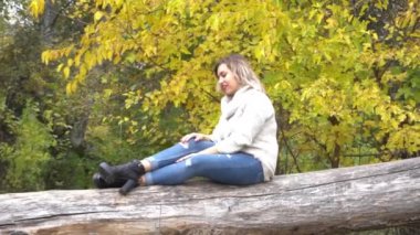 Güzel sarışın kadın güzel bir sonbahar gününde parkta poz veriyor..