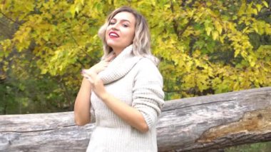 Slow Motion Autumn kadını parkta eğleniyor ve gülümsüyor. Genç kadın portresi.