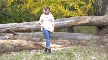 Güneşli bir sonbahar gününde parkta gülümseyen genç bir kadın.