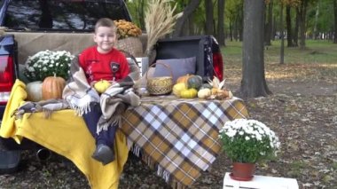 Slow Motion Boy sitting in the back of the car holding pumpkins in autumn