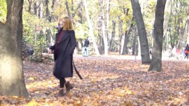 Slow Motion güzel mutlu genç bir kadın sonbahar parkında yürüyor.