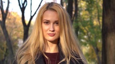 Sonbahar yapraklarıyla parkta güzel güzel gülümseyen genç bir kadın. Sonbahar sezonu. Aut