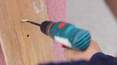 Tanınmayan bir işçi Neiva, Huila, Kolombiya 'daki bir marangoz atölyesinde kalın bir matkapla kablosuz bir elektrikli matkap ile tahta deliyor. Sanayi ve el yapımı kavramı