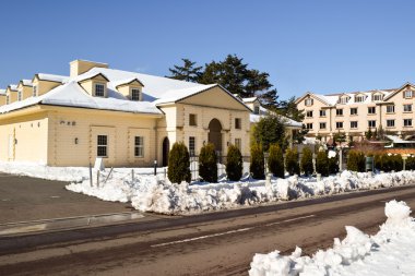 İki katlı tuğla bina, çit, çit ağaçlar, kar ve yol