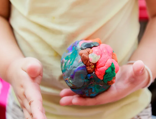 Ball of multicolor play dough on hand
